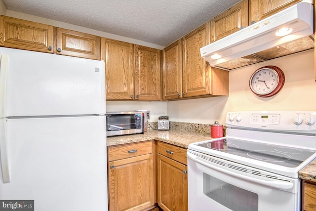 kitchen with a textured ceiling, white appliances, brown cabinets, and under cabinet range hood