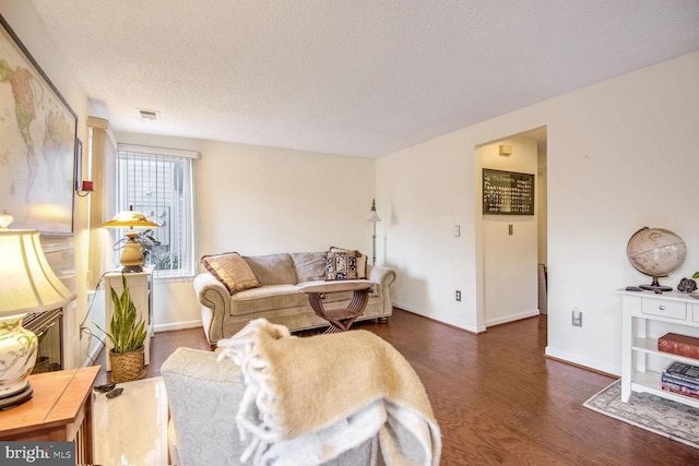 living room featuring visible vents, a textured ceiling, baseboards, and wood finished floors