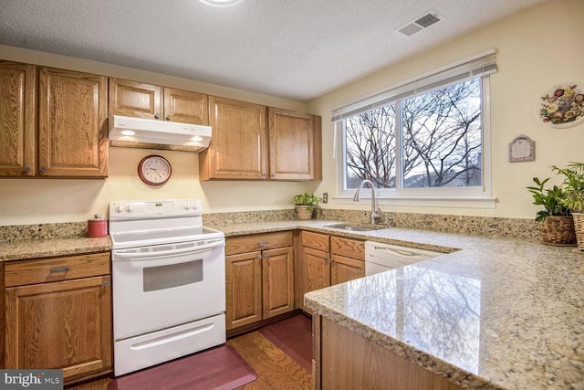 kitchen with white appliances, visible vents, light countertops, under cabinet range hood, and a sink