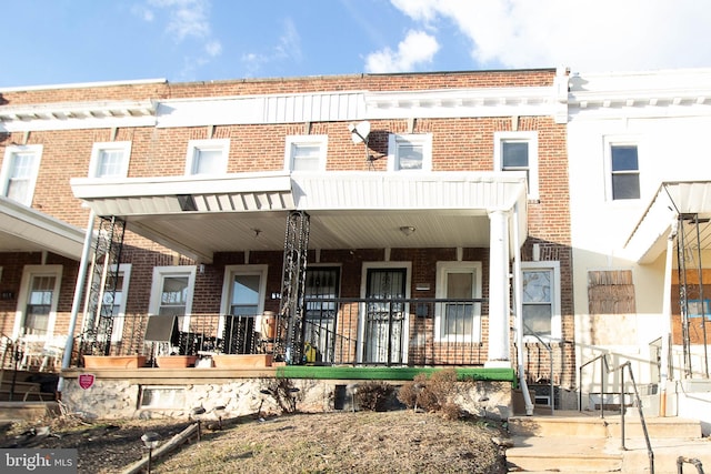 view of property featuring a porch and brick siding