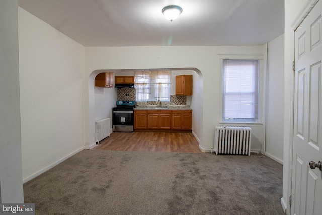 kitchen with carpet flooring, backsplash, radiator heating unit, and stainless steel electric stove