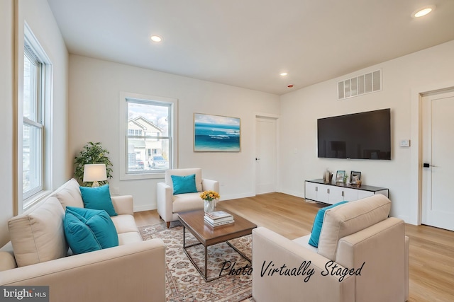 living area featuring a wealth of natural light, visible vents, and light wood-style flooring