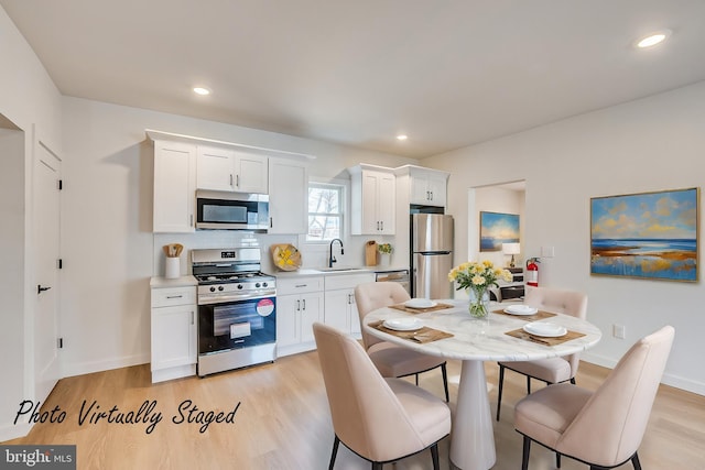 kitchen with white cabinetry, stainless steel appliances, a sink, and light countertops