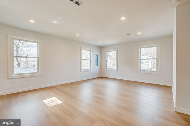 empty room featuring light wood-style floors, recessed lighting, visible vents, and baseboards