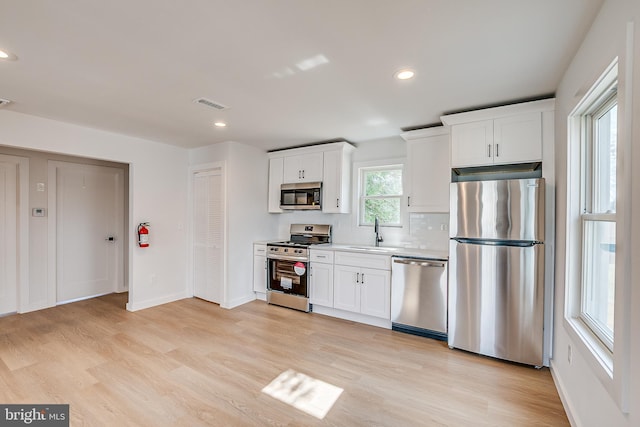 kitchen featuring light wood finished floors, visible vents, white cabinets, appliances with stainless steel finishes, and a sink