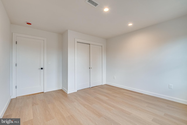 unfurnished bedroom with recessed lighting, a closet, visible vents, light wood-type flooring, and baseboards