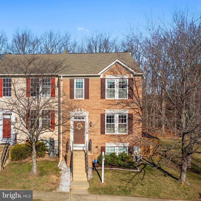 view of property featuring brick siding and a front yard