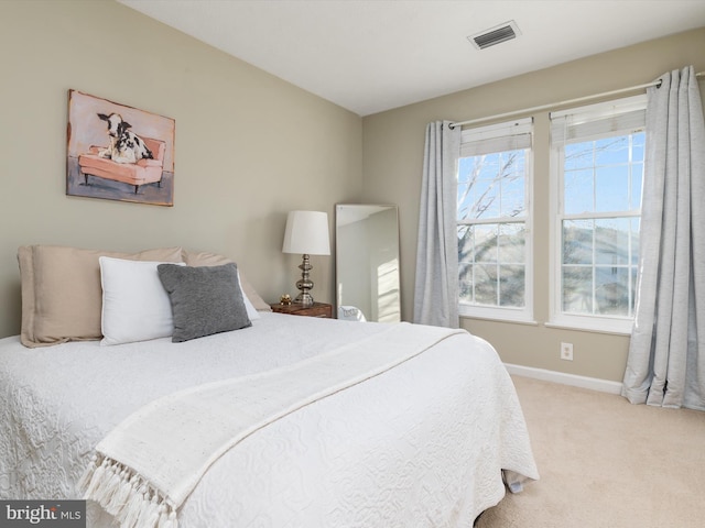 bedroom with baseboards, visible vents, and light carpet