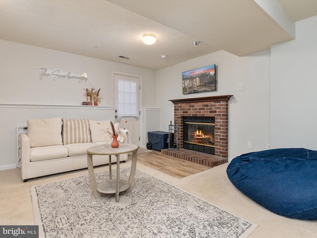 carpeted living area with a brick fireplace, baseboards, visible vents, and a textured ceiling