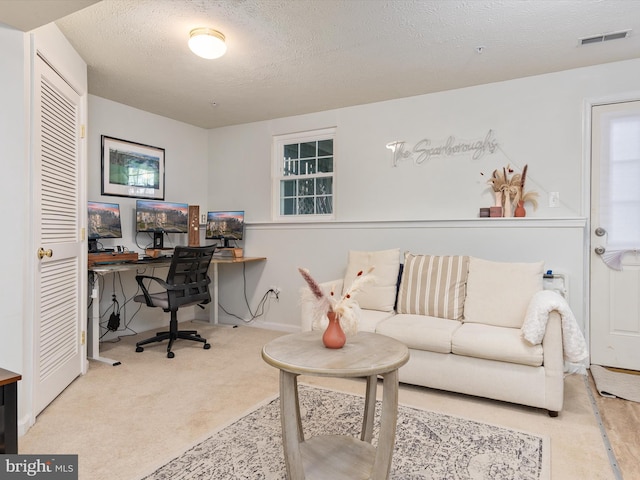 carpeted office space featuring visible vents and a textured ceiling