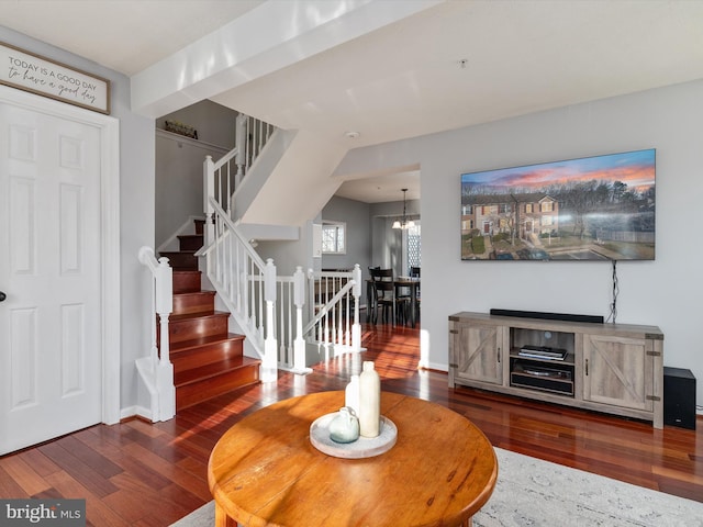 living area with hardwood / wood-style floors, an inviting chandelier, stairway, and baseboards