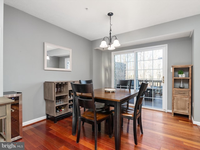 dining area featuring wine cooler, a chandelier, baseboards, and hardwood / wood-style flooring