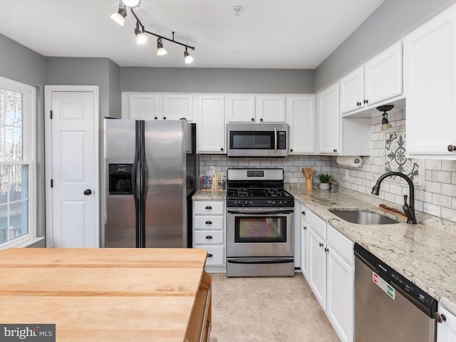 kitchen featuring a sink, stainless steel appliances, backsplash, and white cabinets