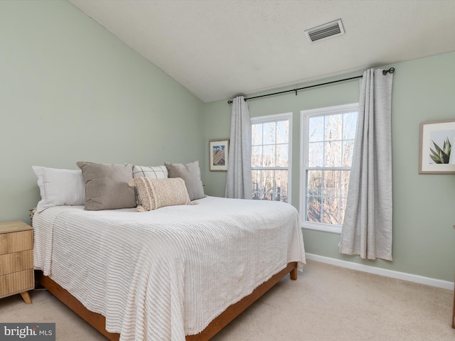 bedroom with vaulted ceiling, baseboards, visible vents, and light carpet