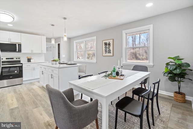 dining room with a healthy amount of sunlight, light wood-style flooring, and baseboards