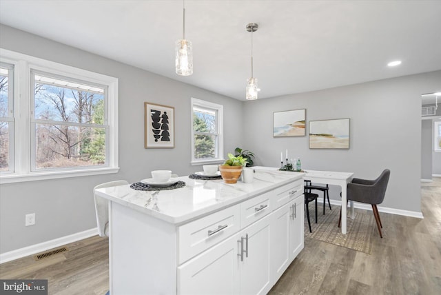 kitchen featuring white cabinetry, light wood-style floors, baseboards, and visible vents