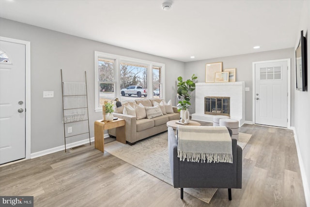 living room with light wood-type flooring, a fireplace, and baseboards