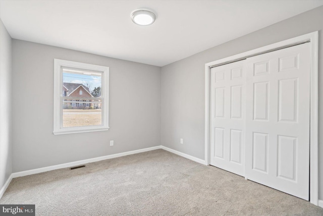 unfurnished bedroom with carpet, a closet, visible vents, and baseboards