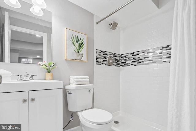 bathroom featuring a tile shower, vanity, and toilet