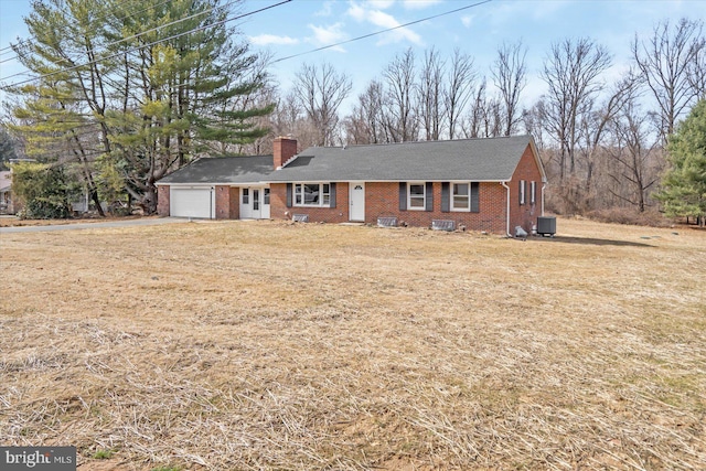 ranch-style home featuring a garage, central air condition unit, a chimney, and brick siding