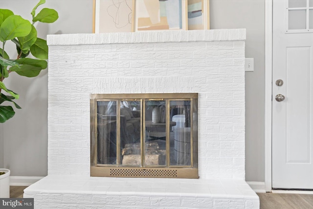 room details featuring wood finished floors, a glass covered fireplace, and baseboards