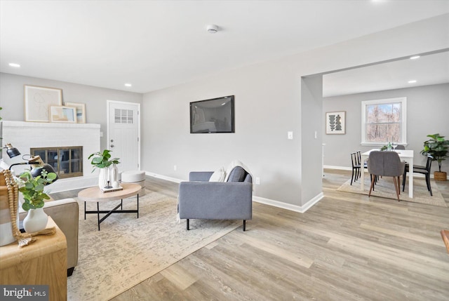 living area with recessed lighting, a brick fireplace, baseboards, and wood finished floors