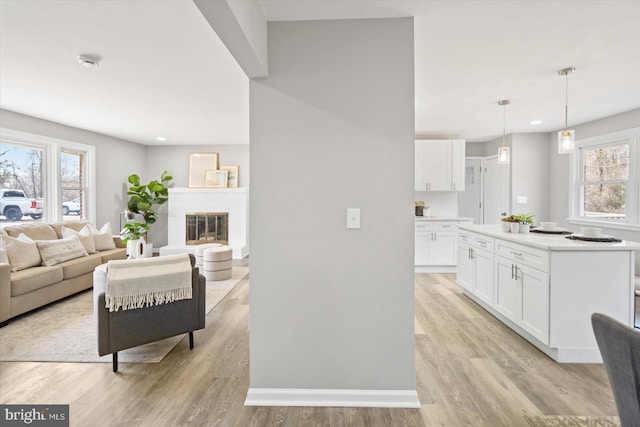 living area with light wood-style floors, a fireplace, and baseboards