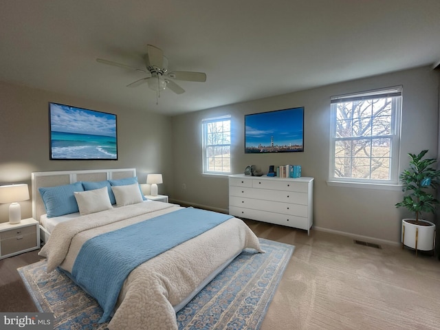 carpeted bedroom featuring a ceiling fan, visible vents, and baseboards