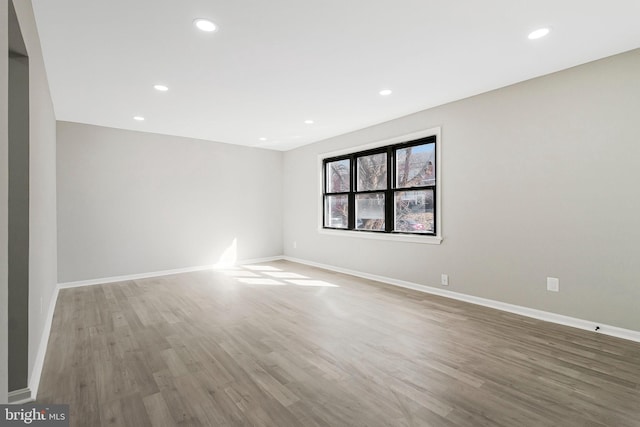 spare room featuring recessed lighting, baseboards, and wood finished floors