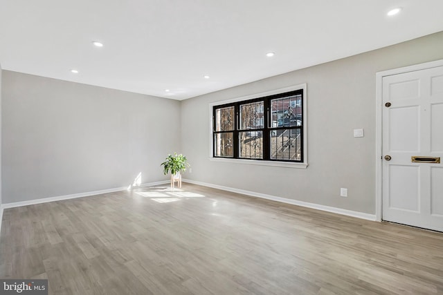 spare room featuring recessed lighting, light wood finished floors, and baseboards