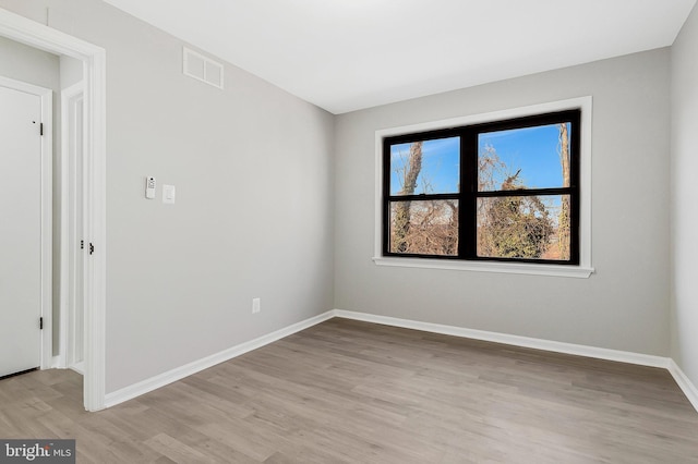 empty room with light wood-type flooring, visible vents, and baseboards