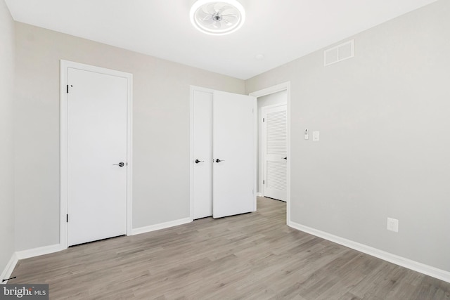 unfurnished bedroom with visible vents, light wood-style flooring, and baseboards