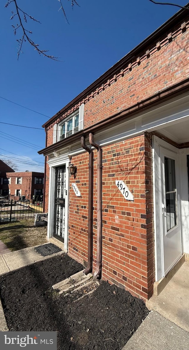 entrance to property with brick siding and fence