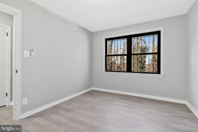 spare room featuring baseboards, visible vents, and wood finished floors