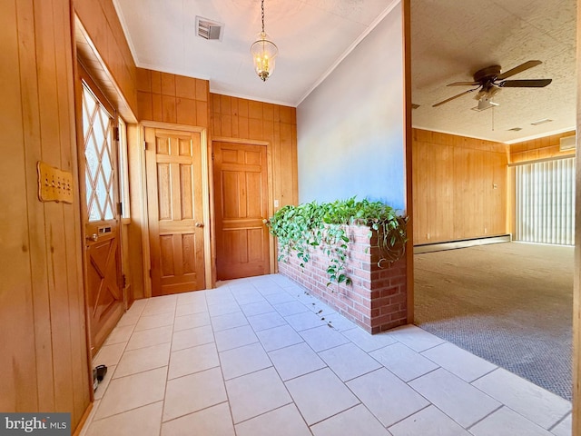 entrance foyer with visible vents, ornamental molding, a baseboard heating unit, carpet, and wood walls