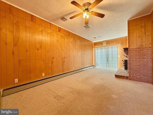 unfurnished living room with wooden walls, visible vents, a baseboard heating unit, carpet, and a ceiling fan