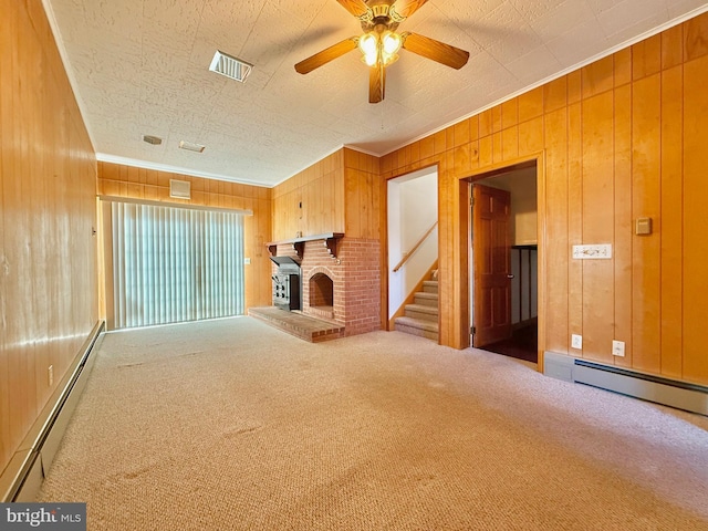 unfurnished living room featuring visible vents, wood walls, a baseboard heating unit, and carpet