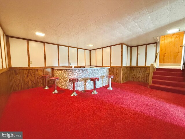 miscellaneous room featuring wainscoting, a dry bar, stairs, and carpet floors