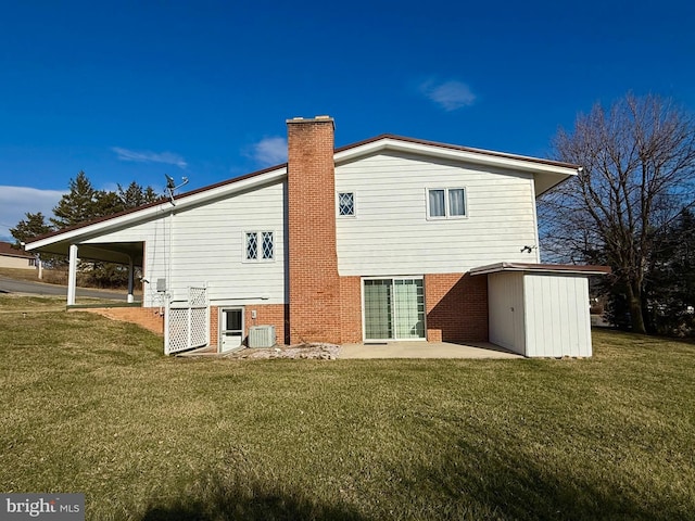 rear view of house featuring brick siding, central air condition unit, a chimney, and a yard