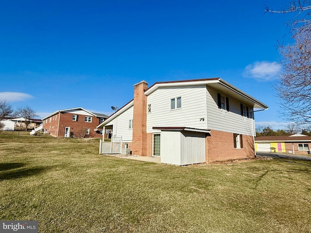 back of property featuring a yard, brick siding, and a chimney