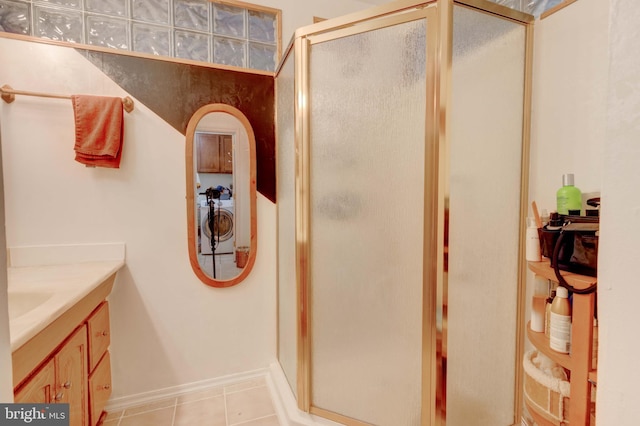 bathroom featuring vanity, tile patterned floors, baseboards, and a stall shower