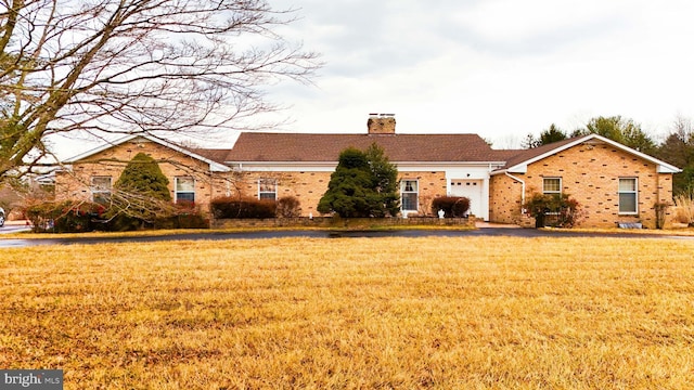 view of front of home with a front yard, brick siding, and a chimney