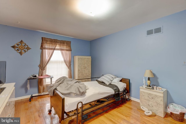 bedroom with visible vents, wood-type flooring, and baseboards