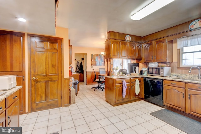 kitchen with stainless steel microwave, dishwasher, brown cabinets, a peninsula, and a sink