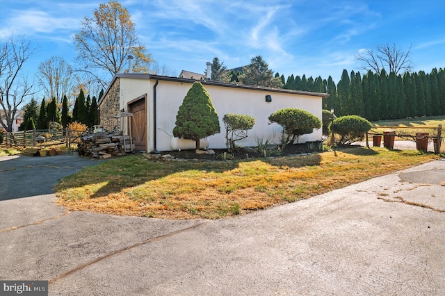 view of home's exterior featuring driveway, an attached garage, fence, and stucco siding