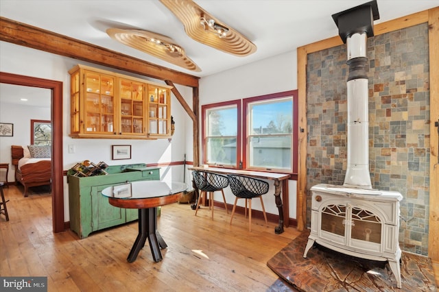 interior space featuring light wood-type flooring, a wood stove, and baseboards