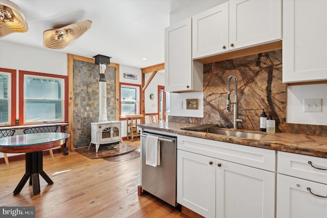 kitchen featuring light wood-style flooring, a sink, white cabinets, stainless steel dishwasher, and decorative backsplash