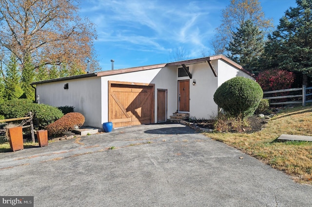 view of outbuilding with a garage, fence, aphalt driveway, and entry steps