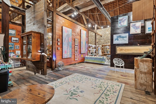 interior space featuring wooden walls, beamed ceiling, a towering ceiling, and hardwood / wood-style flooring