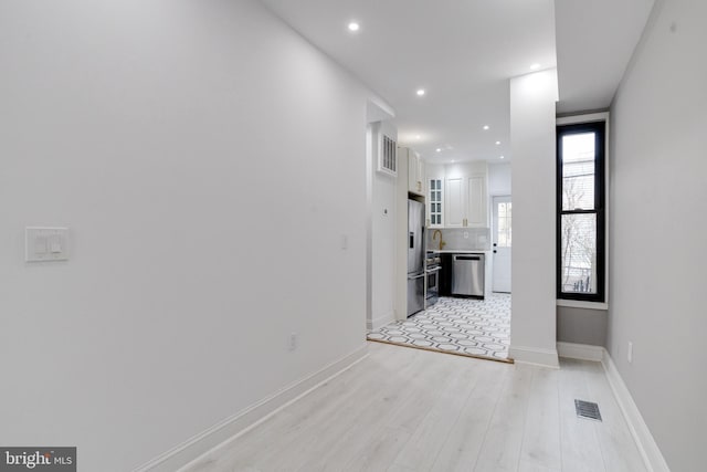 hallway featuring light wood-style floors, recessed lighting, visible vents, and baseboards